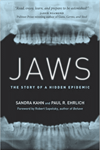 The book cover for "Jaws: The story of a Hidden Epidemic." An X-ray that appears to be coming from the inside of the mouth and looking out between the teeth. You can see the upper teeth connecting to the upper jaw and the lower teeth connecting to the lower jaw.