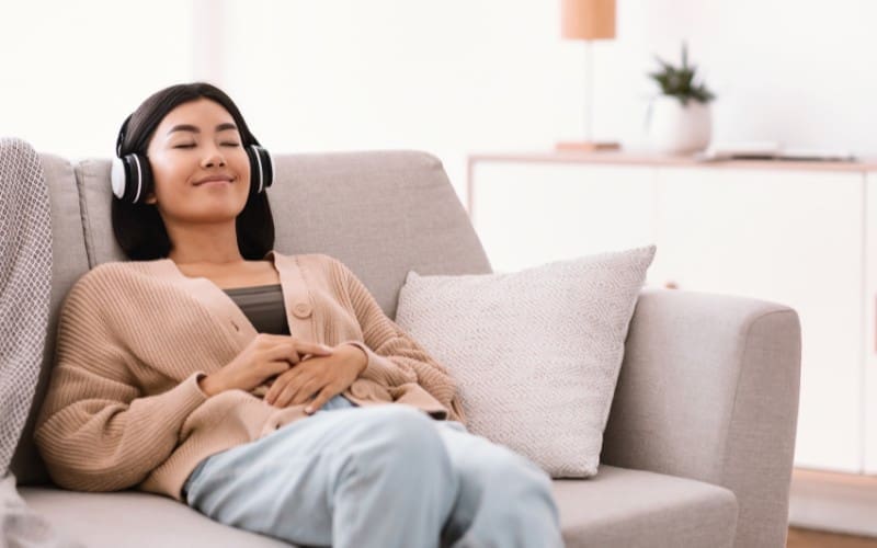 A person listening to music with headphones is sitting on a couch.